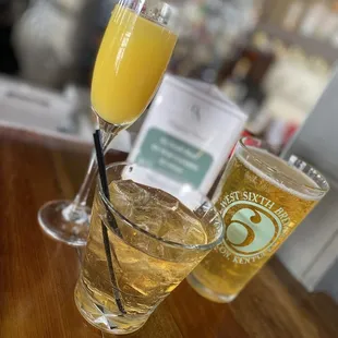 a glass of orange juice and two glasses of beer