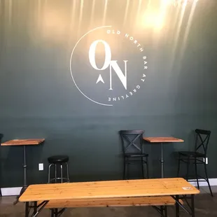tables and chairs in front of a green wall