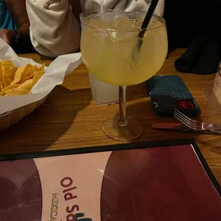 a woman sitting at a table with a drink and chips