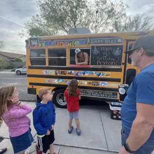 a group of children standing in front of a school bus