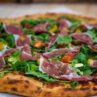 a pizza with prosciutto and arugula
