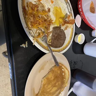 Two egg breakfast with sausage hash browns and a biscuit, one pancake