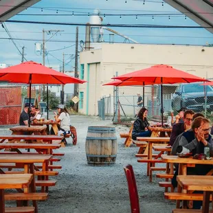 a group of people sitting at tables under red umbrellas