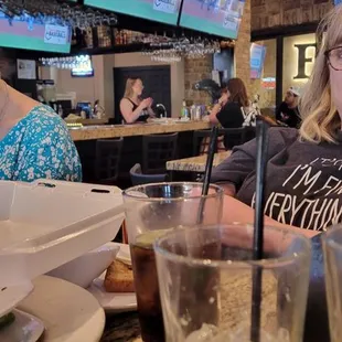 Bartender eating at the bar, serving the uniformed waitstaff alcohol.