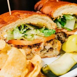 a chicken sandwich with chips and pickles