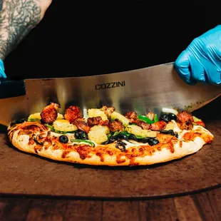 a person cutting a pizza