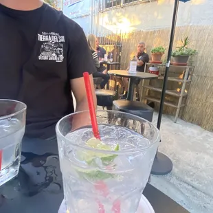 a man sitting at a table with a glass of water and a red straw in front of him