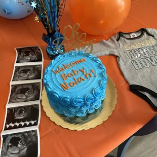 Circular Vanilla Cake w Blue/Orange Buttercream Icing. Bluish/White filling inside cake.