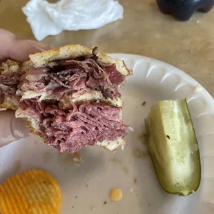 a hand holding a half eaten sandwich