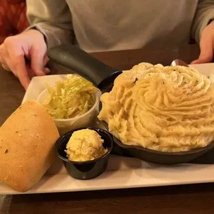 a plate of mashed potatoes and a roll