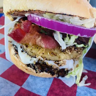 a burger with onion, lettuce, and bacon