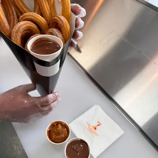 a person holding a container of churros