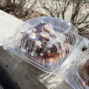 two glazed donuts in plastic containers