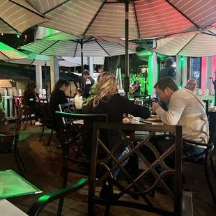 a group of people sitting at a table under an umbrella