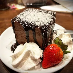 a slice of chocolate cake with whipped cream and strawberries