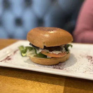 a burger on a white plate on a wooden table