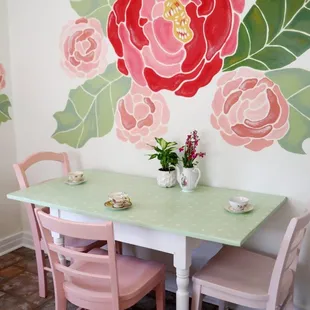 a table and chairs in front of a floral mural