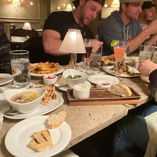 a group of people sitting at a table with food and drinks