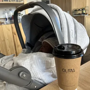 a baby in a stroller and a cup of coffee