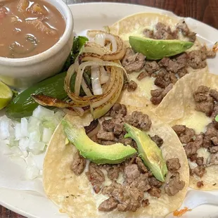 #19 Three Tacos Al Carbon with Charro Beans, grilled onions, avocado &amp; white cheese.