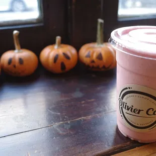 a pink smoothie with pumpkins in the background