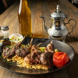 a plate of lamb chops and noodles