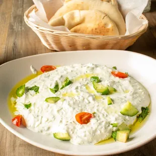 a bowl of dip and a basket of pita bread