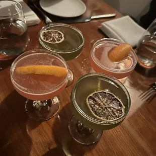 four cocktails on a wooden table