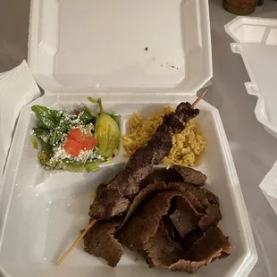 a tray of food with meat skewers and a salad