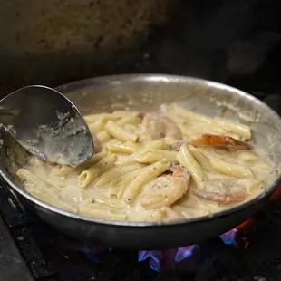 a frying pan with pasta and shrimp
