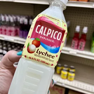 a hand holding a bottle of calpico apple juice