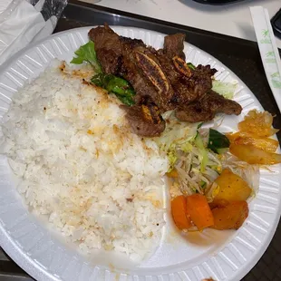 a plate of rice, meat and vegetables