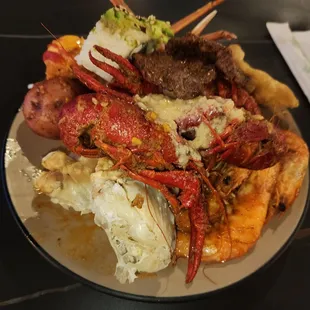 A mix of seafood, sushi and a piece of steak.