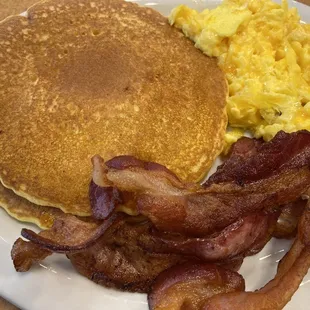 Pancakes, bacon and eggs with cheddar cheese and a cup of coffee