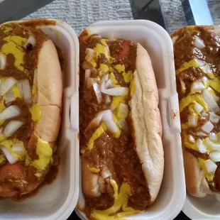 three hotdogs with chili and cheese