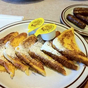 Cinnamon French toast with powder sugar, link sausage on the side.