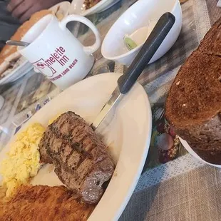 Steak and eggs with wheat bread  blueberry pancakes with strawberry and whipped cream.
