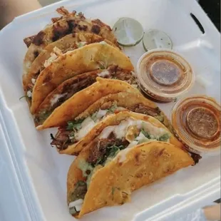 a variety of tacos in a styrofoam container