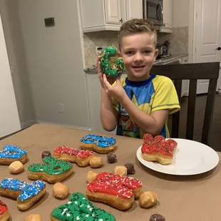 a young boy sitting at a table with a plate of doughnuts