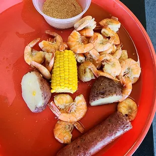 a plate of shrimp, potatoes, corn and sausage