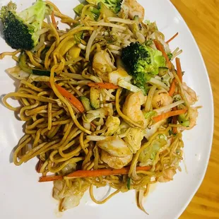 a plate of noodles with shrimp and broccoli