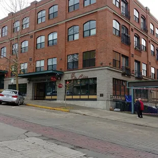 a woman walking down a street in front of a brick building