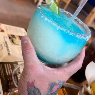a hand holding a blue margarita