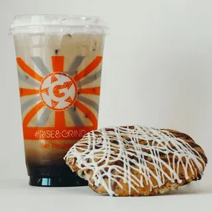a frosted donut next to a cup of coffee