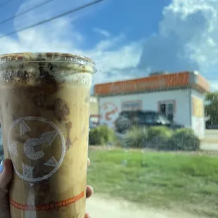 a hand holding a cup of iced coffee