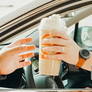 a woman holding a cup of iced coffee