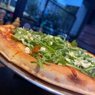 a pizza with greens on it