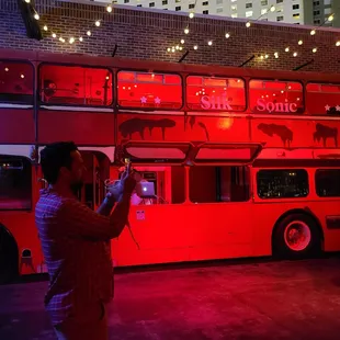 a man taking a picture of a double decker bus