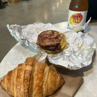 Croissant, breakfast sandwich with bacon, and mango white tea