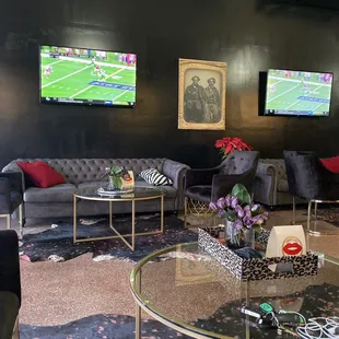 a living room with couches, tables, and televisions